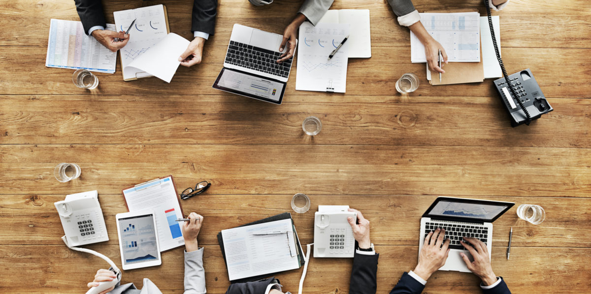 Réunion d'équipe analysant les données financières sur table en bois. Financement dès la commande.